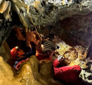 Des enfants equipes de casques et de lampes frontales decouvrent la speleologie a Sisteron dans la grotte 300x277