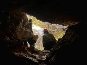 Deux speleologues franchissent un boyaux dans la via souterrata de la Tune 300x225