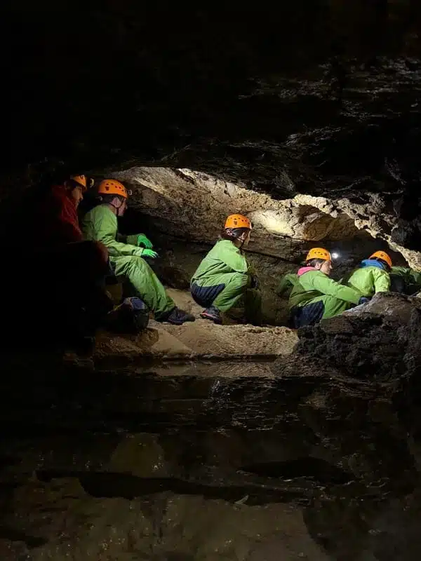 Trois personnes assises au fond dune petite grotte du Devoluy