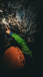 Une personne eclaire avec sa lampe frontale les stalactites de la grotte du Puits des Bans dans le Devoluy 169x300