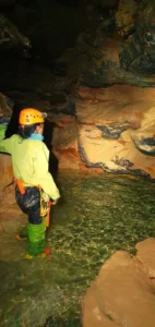 Une personne equipee dune tenue de speleologie eclaire le siphon du Puits des Bans 727x1536 1 142x300