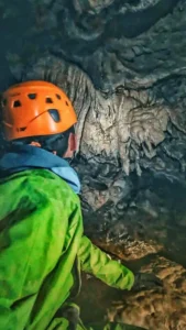 Une personne regarde les stalactites dune grotte du Devoluy 169x300