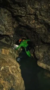 Une personne traverse une vasque deau dans une grotte du Devoluy 169x300