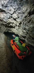 Une personnes equipee dun casque dune lampe frontale et dune combinaison de speleologie est allongee sur un petit 725x1536 1 142x300