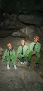 trois personnes en combinaison de speleologie assises dans une grande salle dune grotte du Devoluy 727x1536 1 142x300