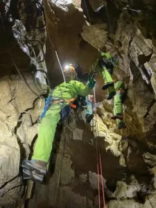 une personne equipee avec du materiel de via ferrata grimpe sur les barreaux pour acceder au pont de singe de la via souterrata 225x300