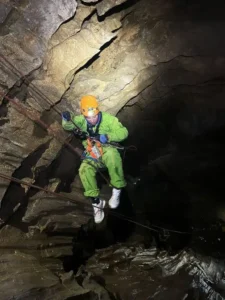 une personne equipee dun casque et dun baudrier descend en rappel un puits de la via souterrata du Devoluy 225x300